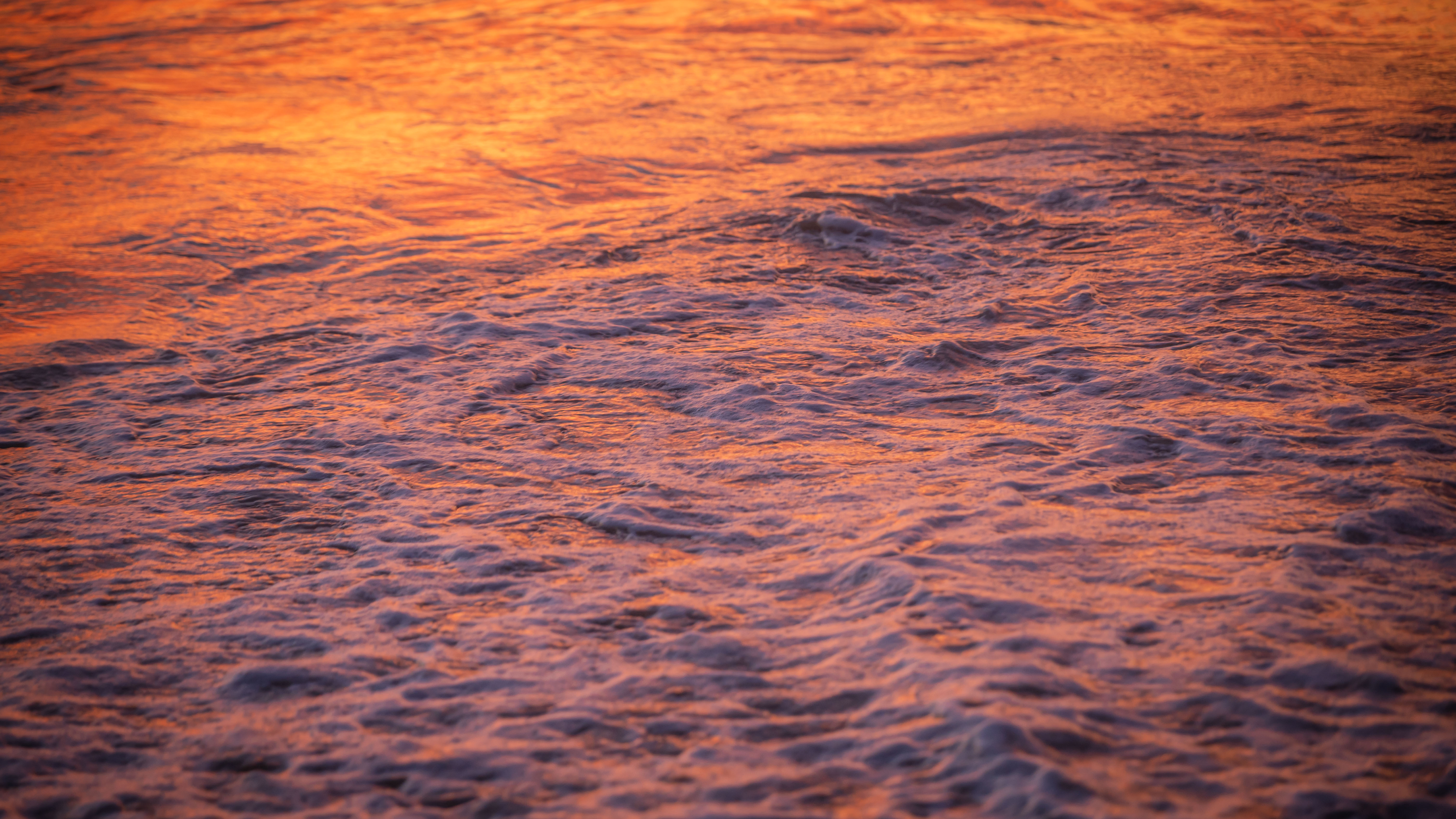 Rippling water reflecting orange and violet evening light